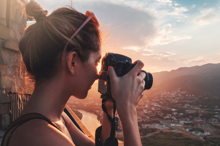 photo editing - a woman holding a camera to take a picture of the scenery