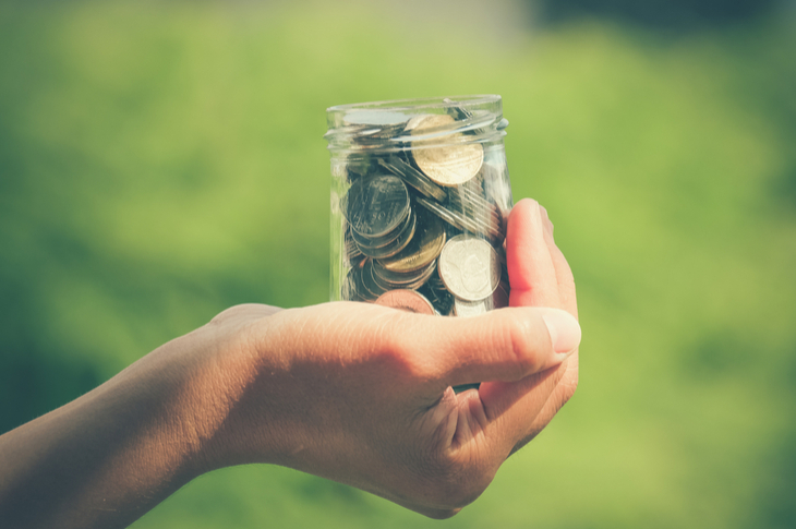 Video Budgeting - A photo of a hand holding a jar of coins - Scatter