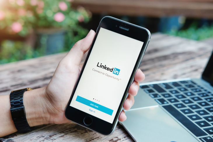 hand holding phone with linkedin app open showing LinkedIn marketing