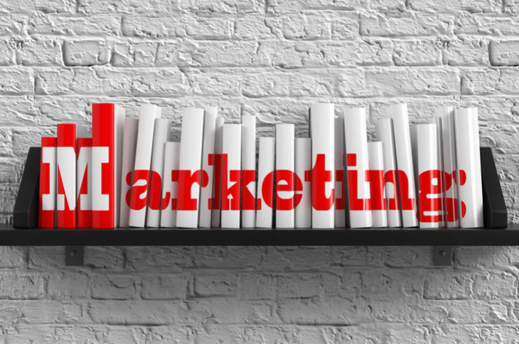 Stack of books indicating the importance of marketing book. The word marketing is written on white books in red colour