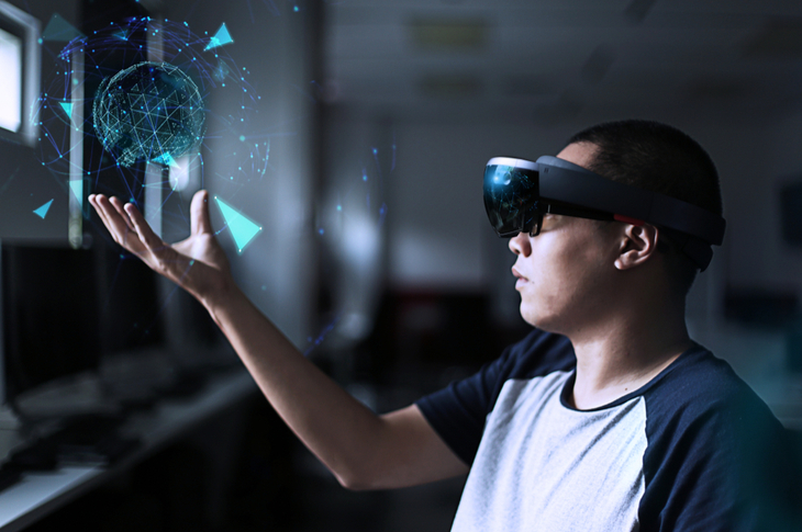 Young man test virtual reality glasses in the lab room with hololens headset. Augmented Reality (AR) concept